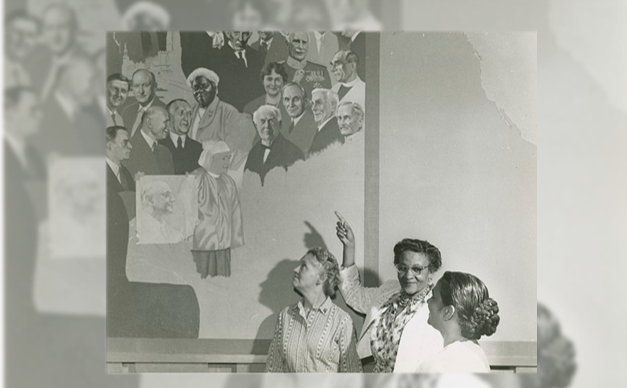 Black and white photograph of Frances Albrier gesturing towards a mural of Mary McLeod Bethune