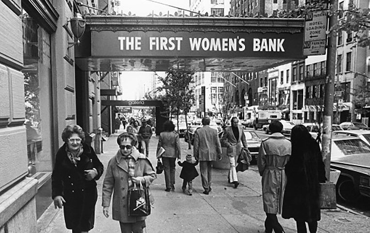 Black and white photograph of the people walking past the entrance to The First Women's Bank, 1975